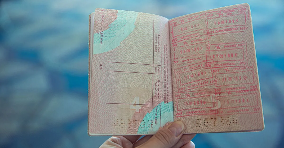 Vue en gros plan d'un passeport ouvert affichant divers timbres de voyage dans un environnement d'aéroport.