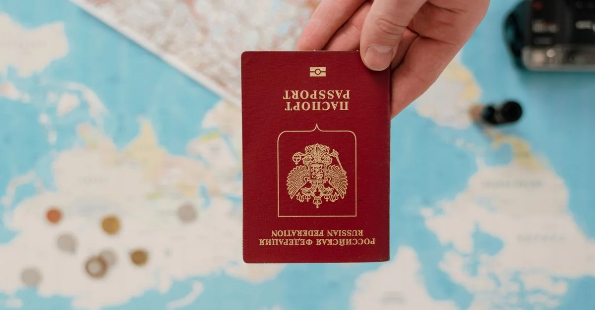 Une main tenant un passeport russe au-dessus d'une carte, suggérant des préparatifs de voyage.