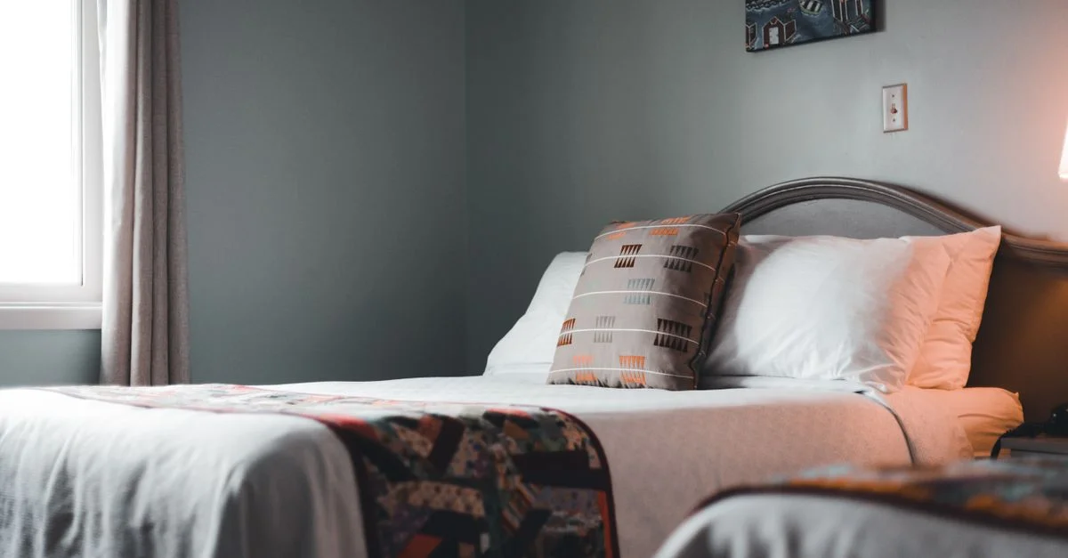 Intérieur de chambre d'hôtel invitant avec un lit soigneusement arrangé et un éclairage doux.