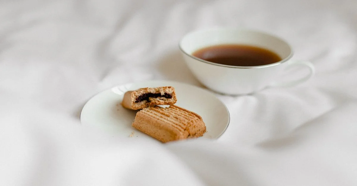 Une scène matinale cosy avec du café et un cookie mordu sur un lit blanc.
