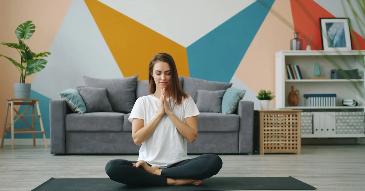 Femme pratiquant le yoga sur un tapis dans un salon élégant au design géométrique.